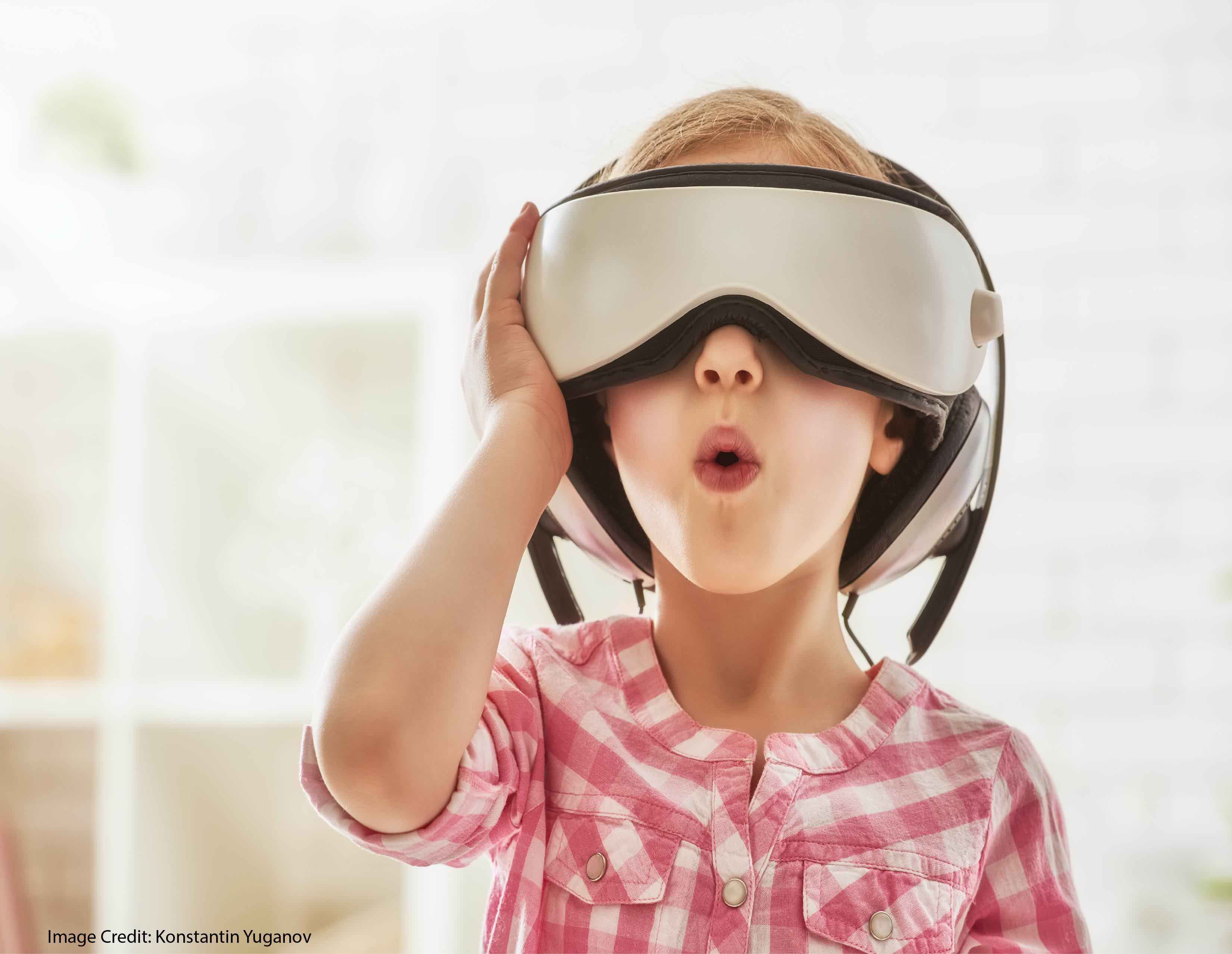 Cute little child girl playing game in virtual reality glasses.