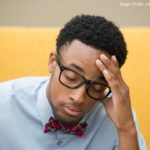 African American student wearing a bow tie, hand to forehead, looking frustrated and disappointed