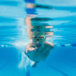 Underwater picture of a young boy swimming directly toward the camera