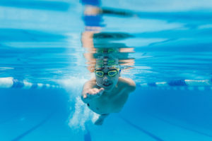 Underwater picture of a young boy swimming directly toward the camera