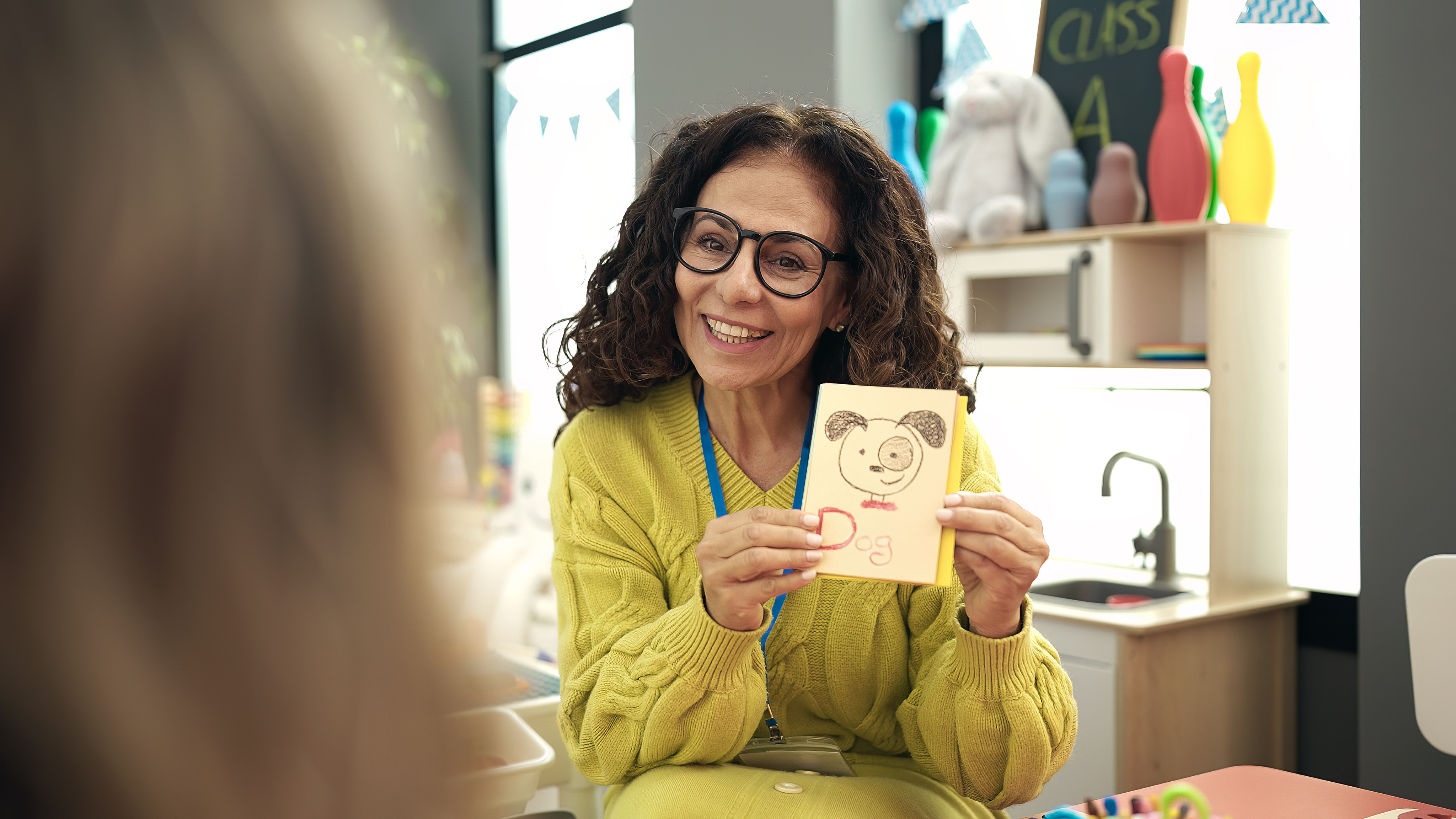 Middle aged preschool teacher having vocabulary lesson at kindergarten