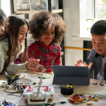 Group of middle-school children working with electrical equipment and an ipad