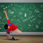 Picture of a student doing acrobatic movement in the classroom while carrying backpack with doodles on the blackboard