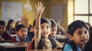 A primary school student wearing a backpack and sitting at a desk raises an eager hand.