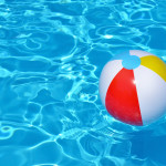 A brighly colored beac ball floating in a vibrantly blue pool