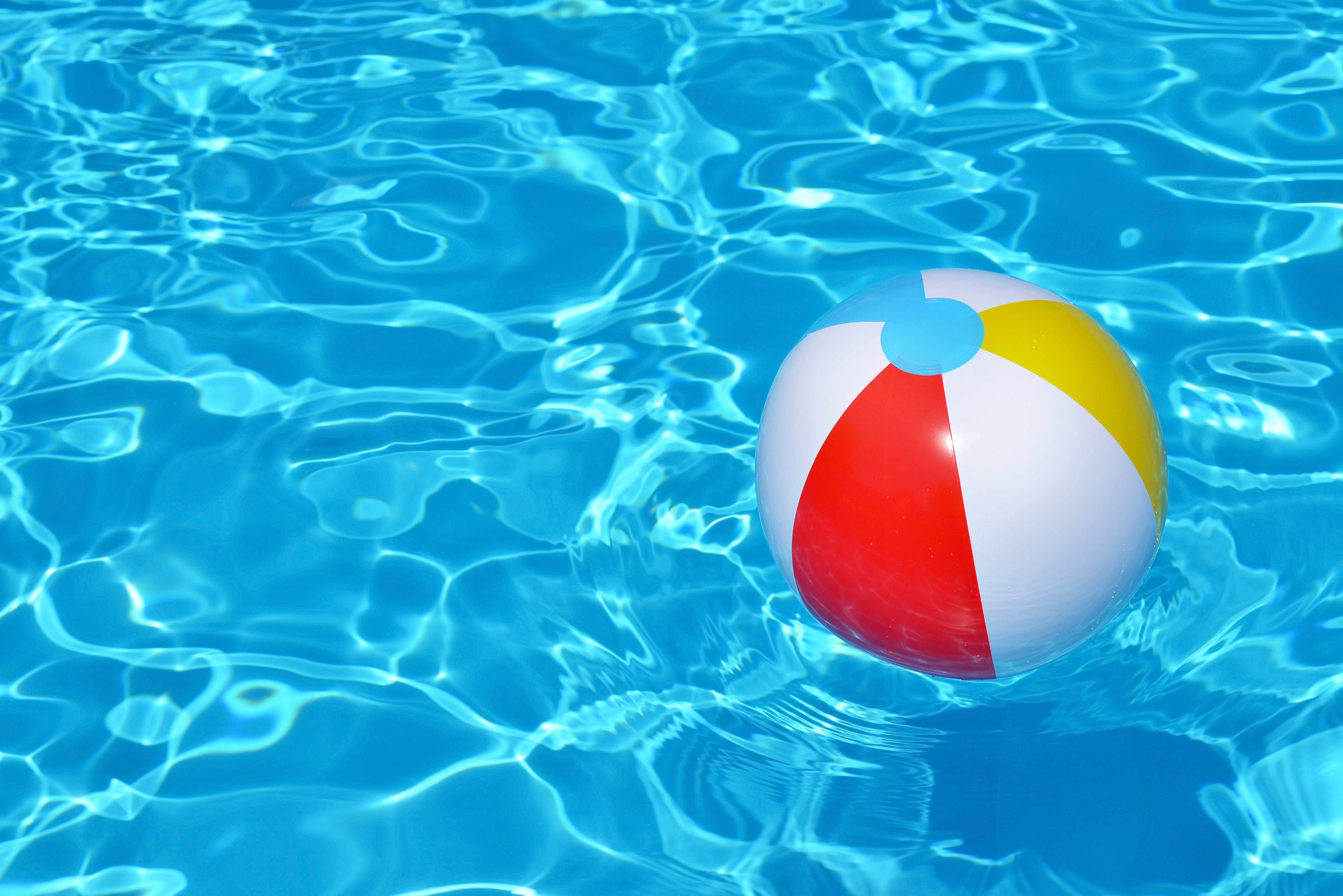 A brighly colored beac ball floating in a vibrantly blue pool