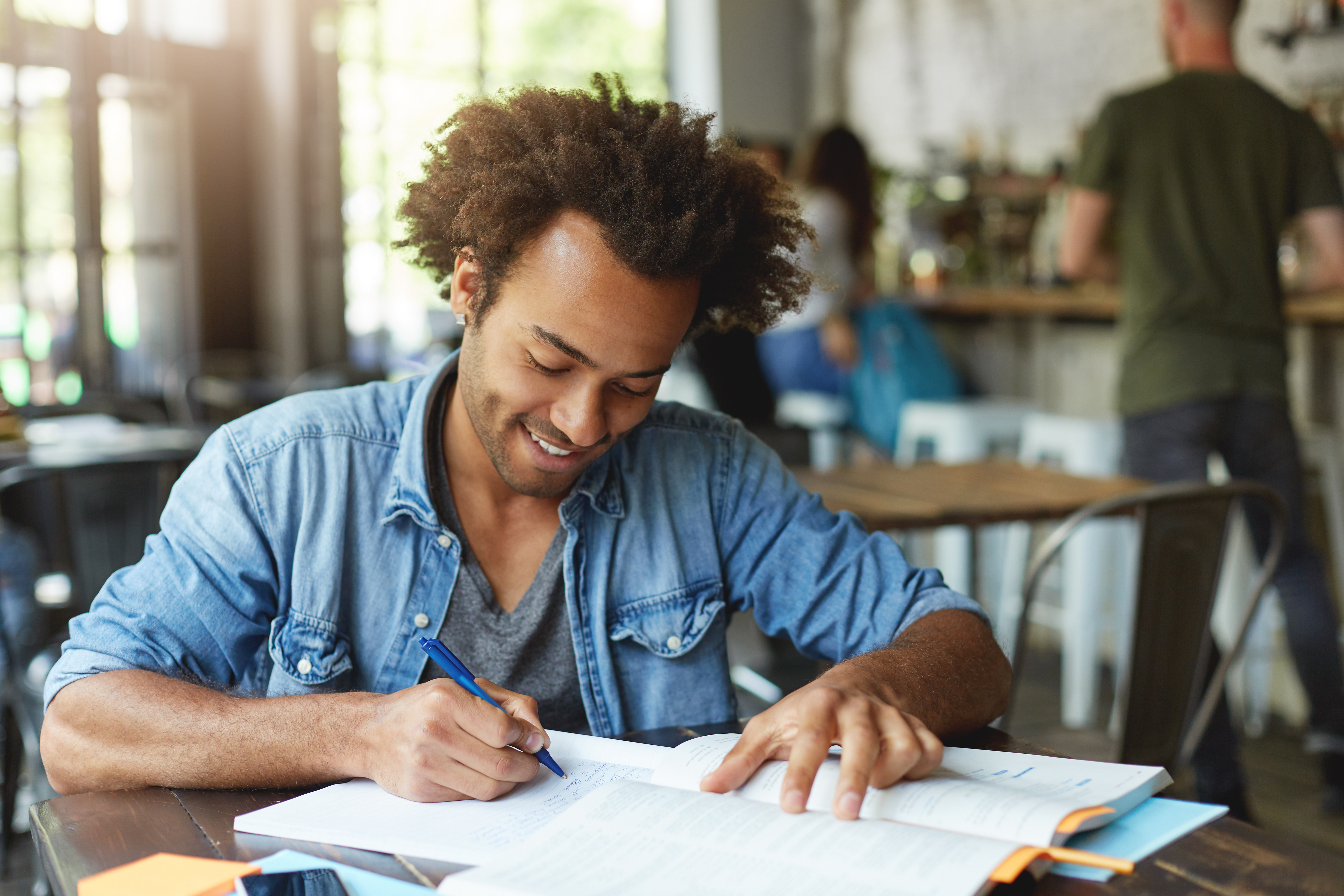 College student smiling while taking notes on while studying