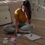 Teenage girl sitting on floor and trying to learn with post-it notes