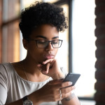 A serious-looking college student examining her phone