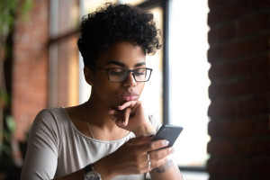 A serious-looking college student examining her phone