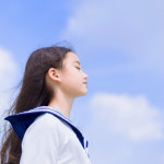 Side view of student girl enjoying summer breeze , smiling with eyes closed