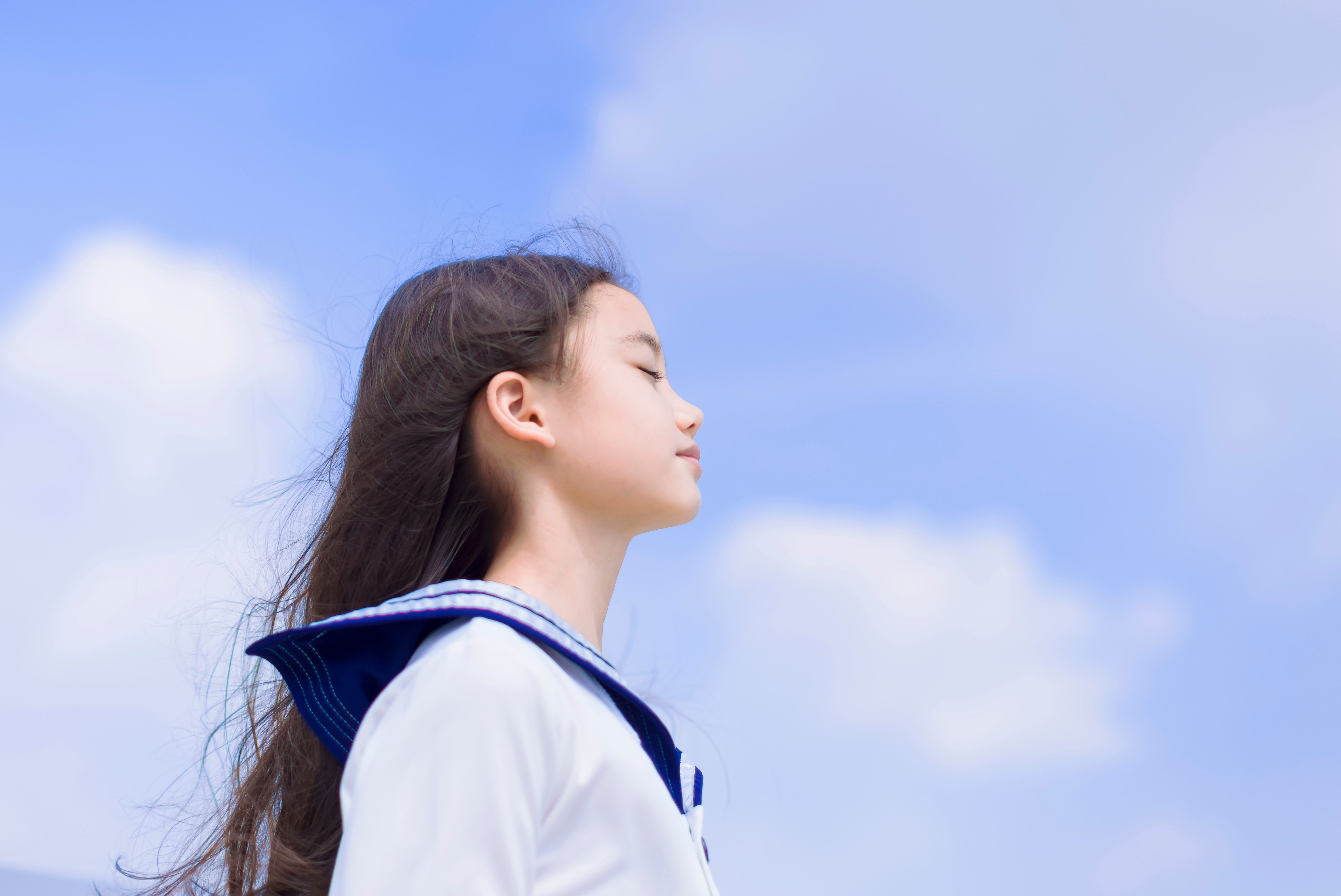 Side view of student girl enjoying summer breeze , smiling with eyes closed