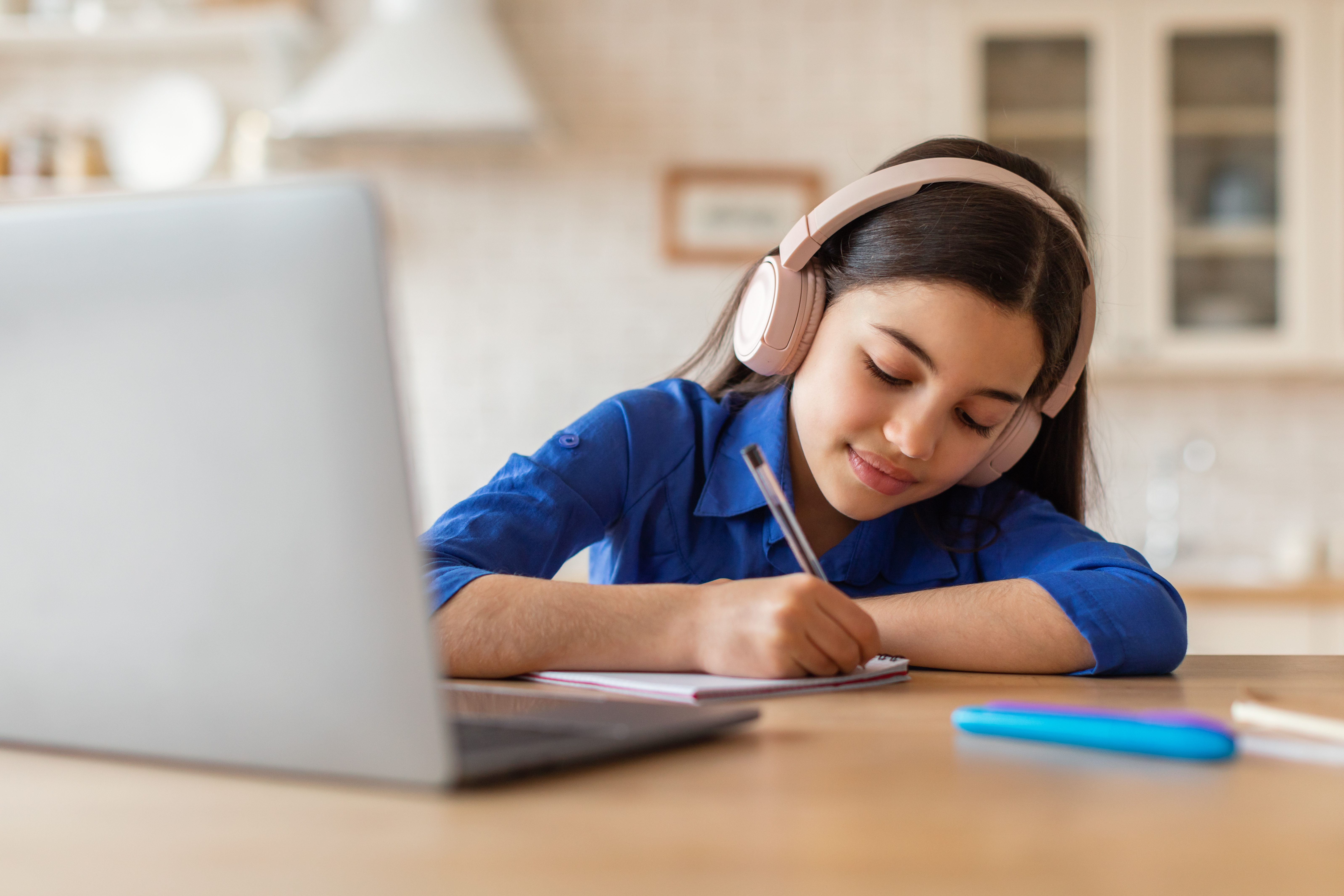 Middle schooler wearing headphones and doing work in front of her laptop at a desk