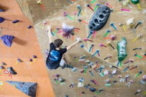 A young rock climber navigating a challenging route with numerous colorful holds, illustrating how learners at different skill levels need different types of support and guidance.
